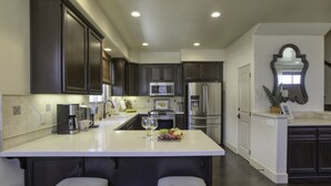 Une cuisine moderne avec des meubles de couleur sombre, un plan de travail blanc et des appareils électroménagers en acier inoxydable.
