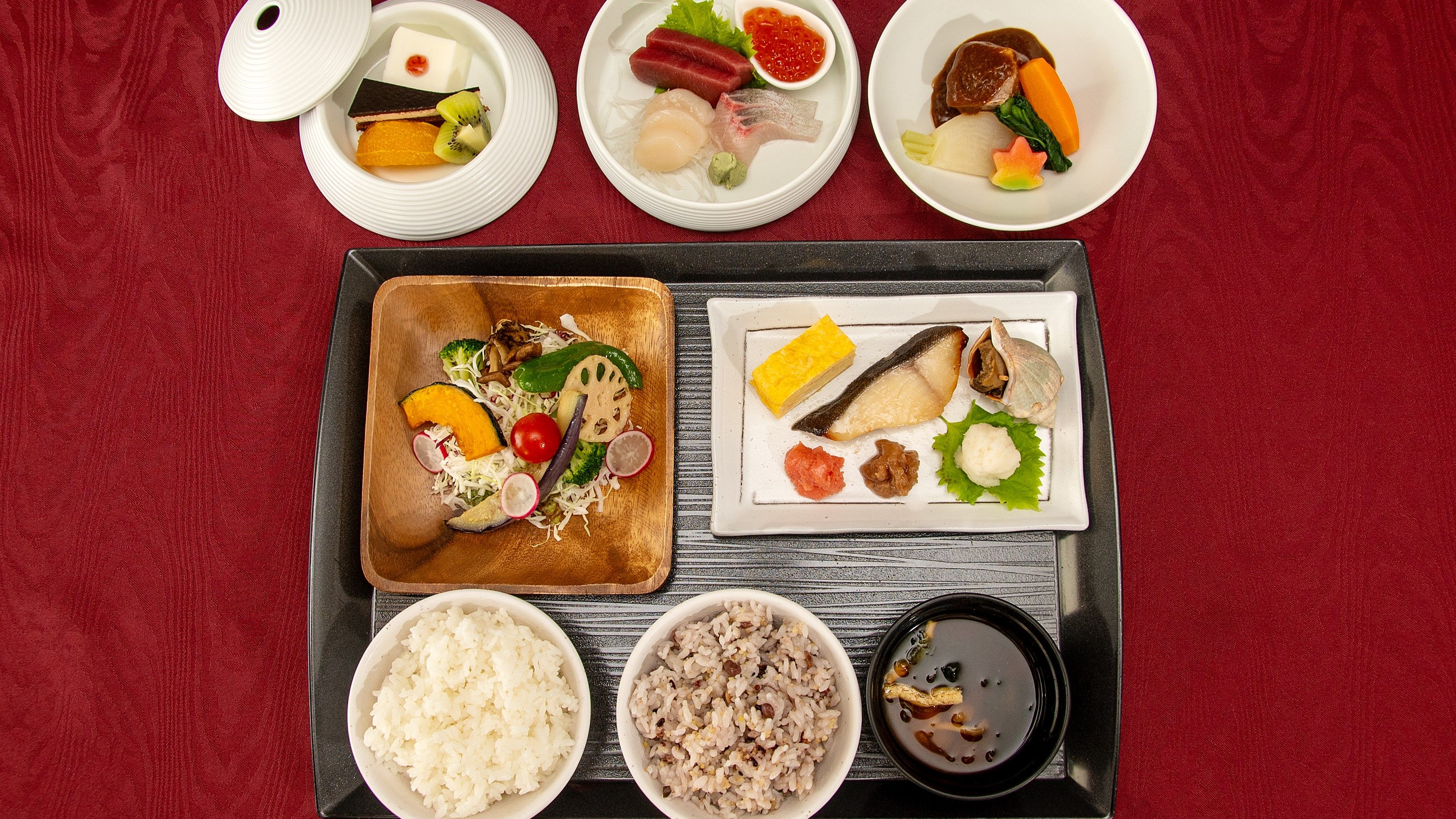 A tray with various Japanese dishes including sashimi, rice, and vegetables.