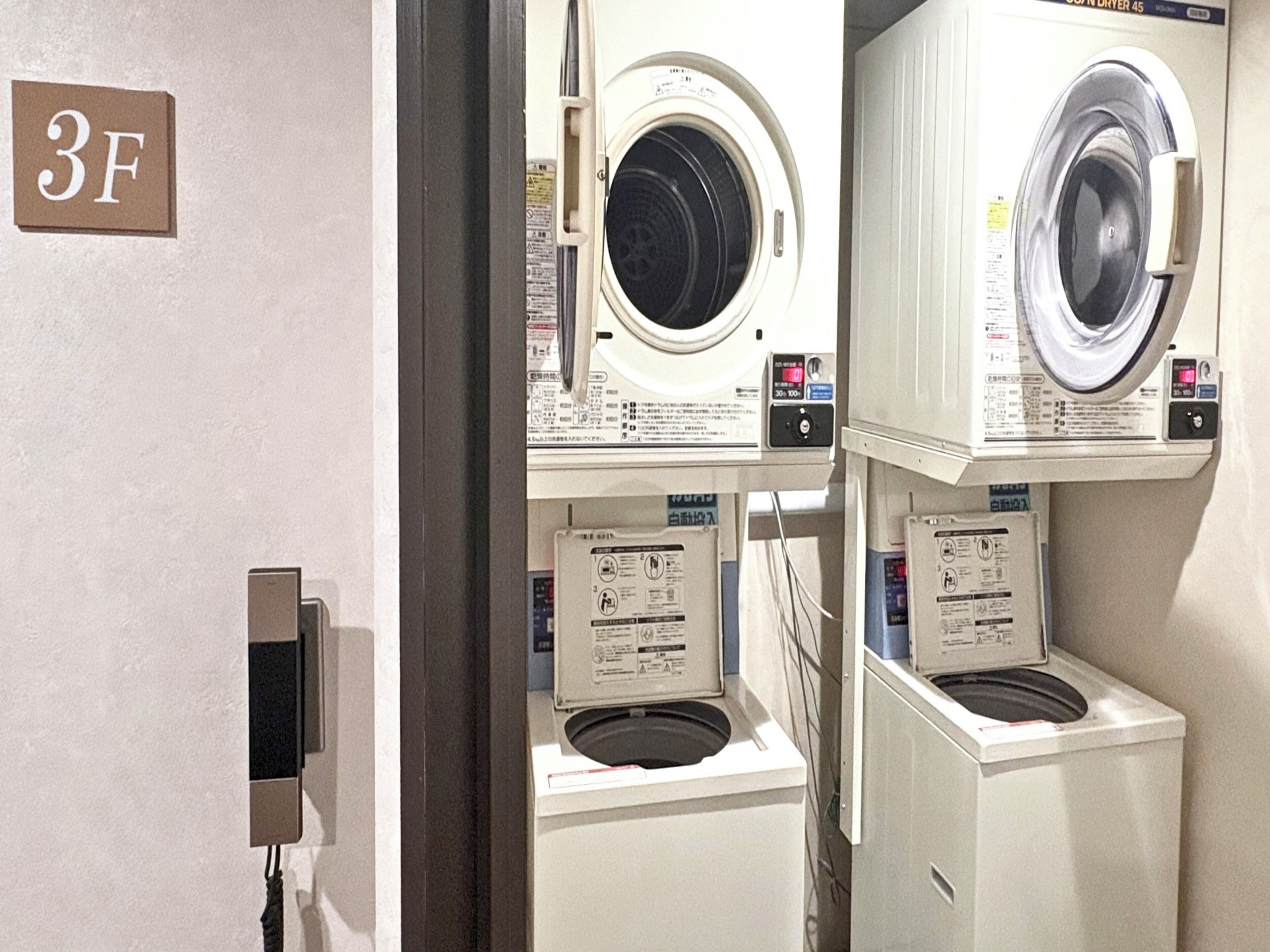 A laundry facility with multiple washing machines, a sign indicating room number 3F, and electrical outlets.