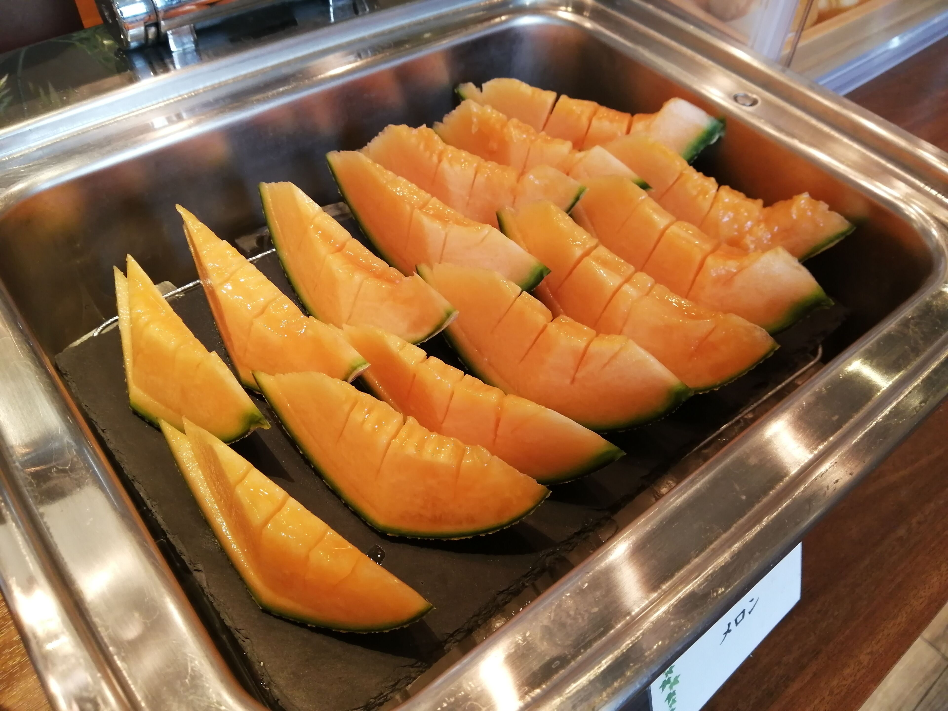 Un plateau en métal sur lequel des tranches de melon cantaloup sont disposées en forme de quadrillage.