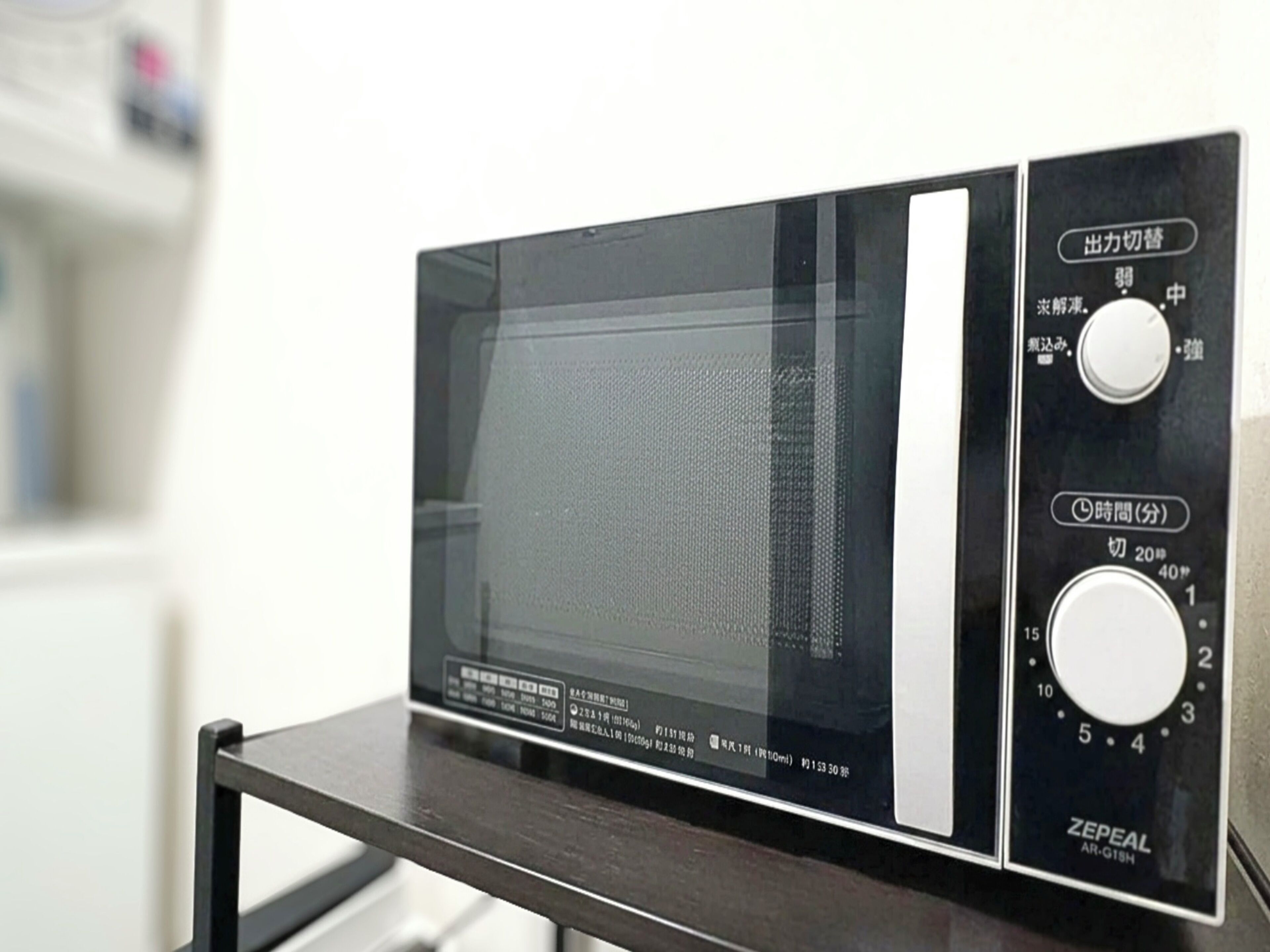 Un microondas sobre un soporte de madera oscura con pantalla digital y perillas de control.
