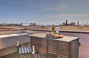 A rooftop terrace with a sink, a table with bread, a bottle of wine, and a glass. - Pismo Awesome Ocean Views - ocean side of Hwy 101 (Pismo Beach)
