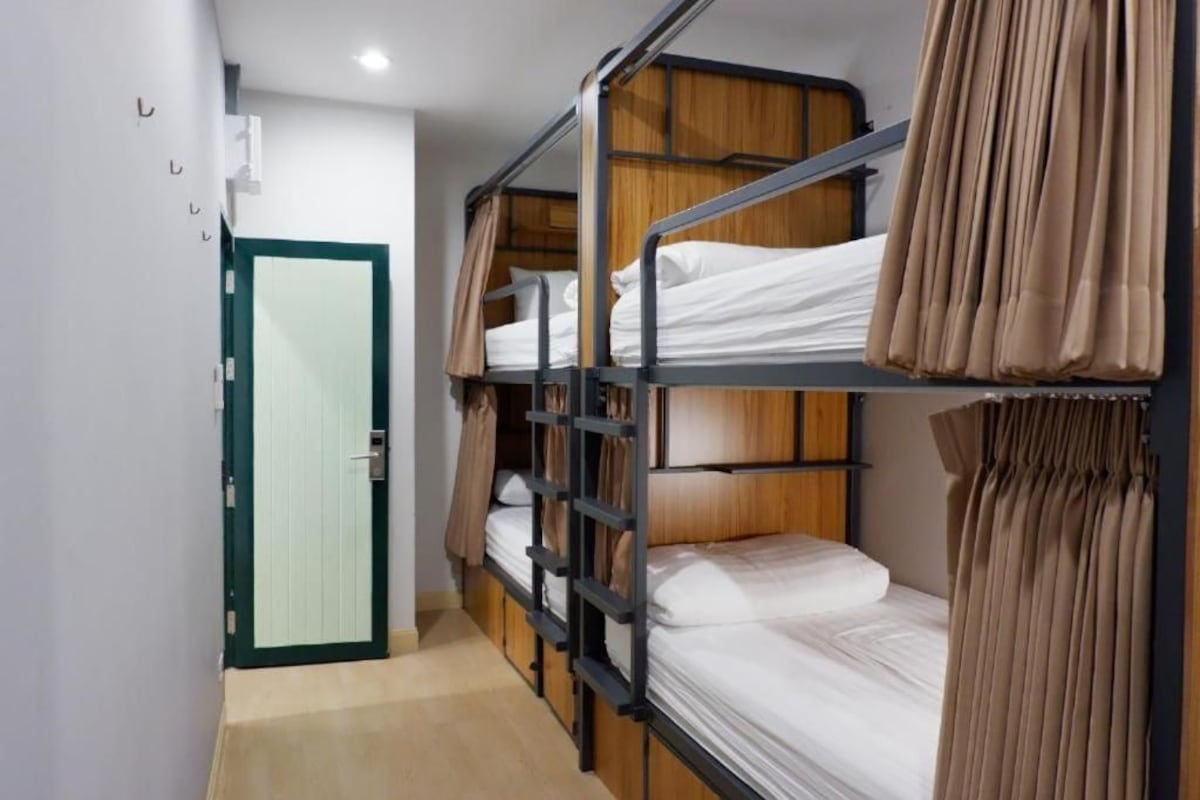 Quarto com beliche, porta verde, guarda-roupa de madeira e cortina.