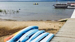 Un muelle de madera con varias kayaks azules y blancas alineadas sobre la arena.