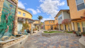 A courtyard with stone walls, a fountain, and a variety of potted plants. - Studio condo with ocean views, steps to the beach (Avila Beach)