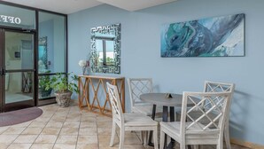 A dining area with a round table and four chairs, a decorative mirror, and a painting on the wall.