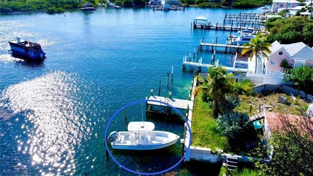 A marina with boats docked, a lighthouse in the background, and a small island with buildings. - Dunwanderin-Historic Cottage in the Heart of Hope Town w/dock (Elbow Cay)