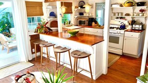 A kitchen with a wooden island, bar stools, a microwave, stove, and various kitchen utensils. - Dunwanderin-Historic Cottage in the Heart of Hope Town w/dock (Elbow Cay)