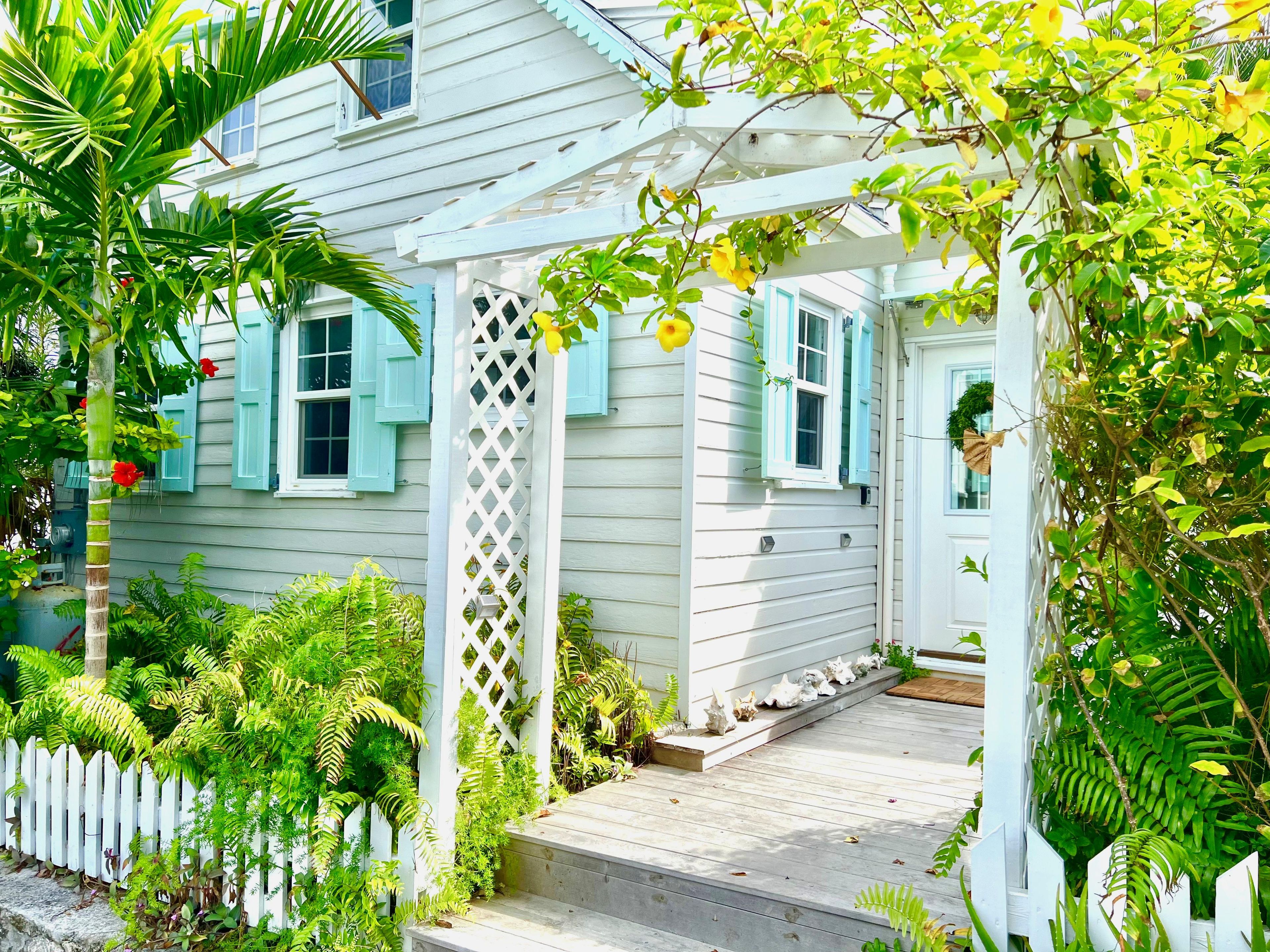 A house with a porch, a white picket fence, and various plants.