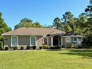 A single-story house with a brown roof, beige walls, and a front porch. - Spacious, fully furnished family friendly 3 bedroom home with private pool. (Lecanto)