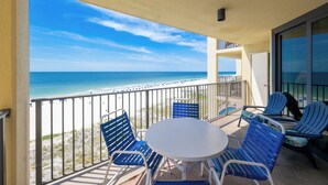 A balcony with a view of the beach and ocean, featuring blue chairs and a small table. - *WEEKLY SPECIALS!* * Phoenix IV 2BR on 6th floor! (Orange Beach)