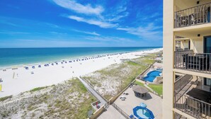 A beach view from a hotel balcony with a pool and lounge chairs. - *WEEKLY SPECIALS!* * Phoenix IV 2BR on 6th floor! (Orange Beach)