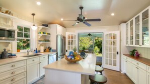 Una cocina moderna con armarios blancos, una isla central y vistas al exterior.
