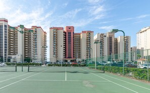 Een tennisbaan omgeven door hoge woontorens.