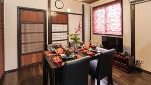 Comedor japonés tradicional con esteras de tatami, una mesa baja y un reloj en la pared.