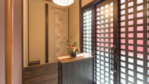 Un área de recepción con mostrador de madera, un arreglo floral y una puerta corredera tradicional con diseño de cuadrícula.