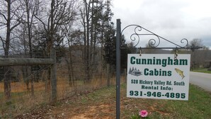 Une enseigne indiquant « Cunningham Cabins », située au 528 Hickory Valley Rd. South, avec le numéro de téléphone suivant : 931-946-4895.