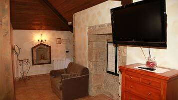 Uma sala de estar acolhedora com lareira de pedra, televisão na parede e um armário de madeira.