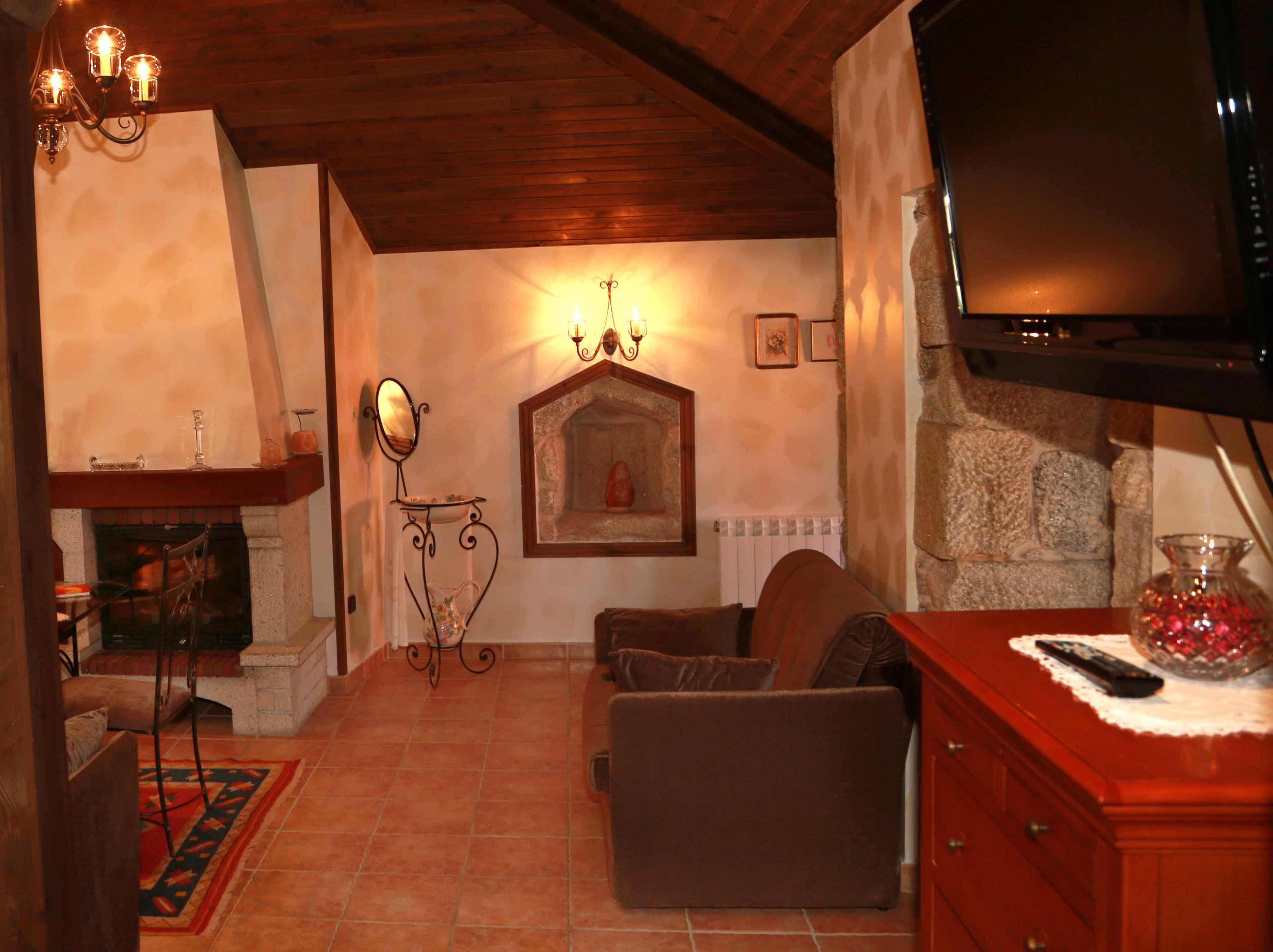 Una sala de estar acogedora con chimenea, televisor y pared de piedra.