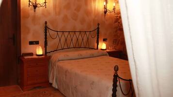 Un dormitorio con una cama, mesitas de noche de madera, una lámpara de noche y apliques de pared.