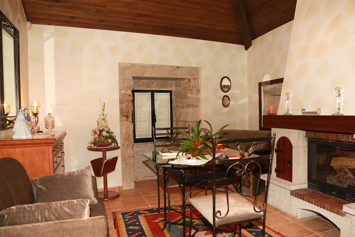 A cozy living room with a fireplace, a dining table with chairs, and a sofa.