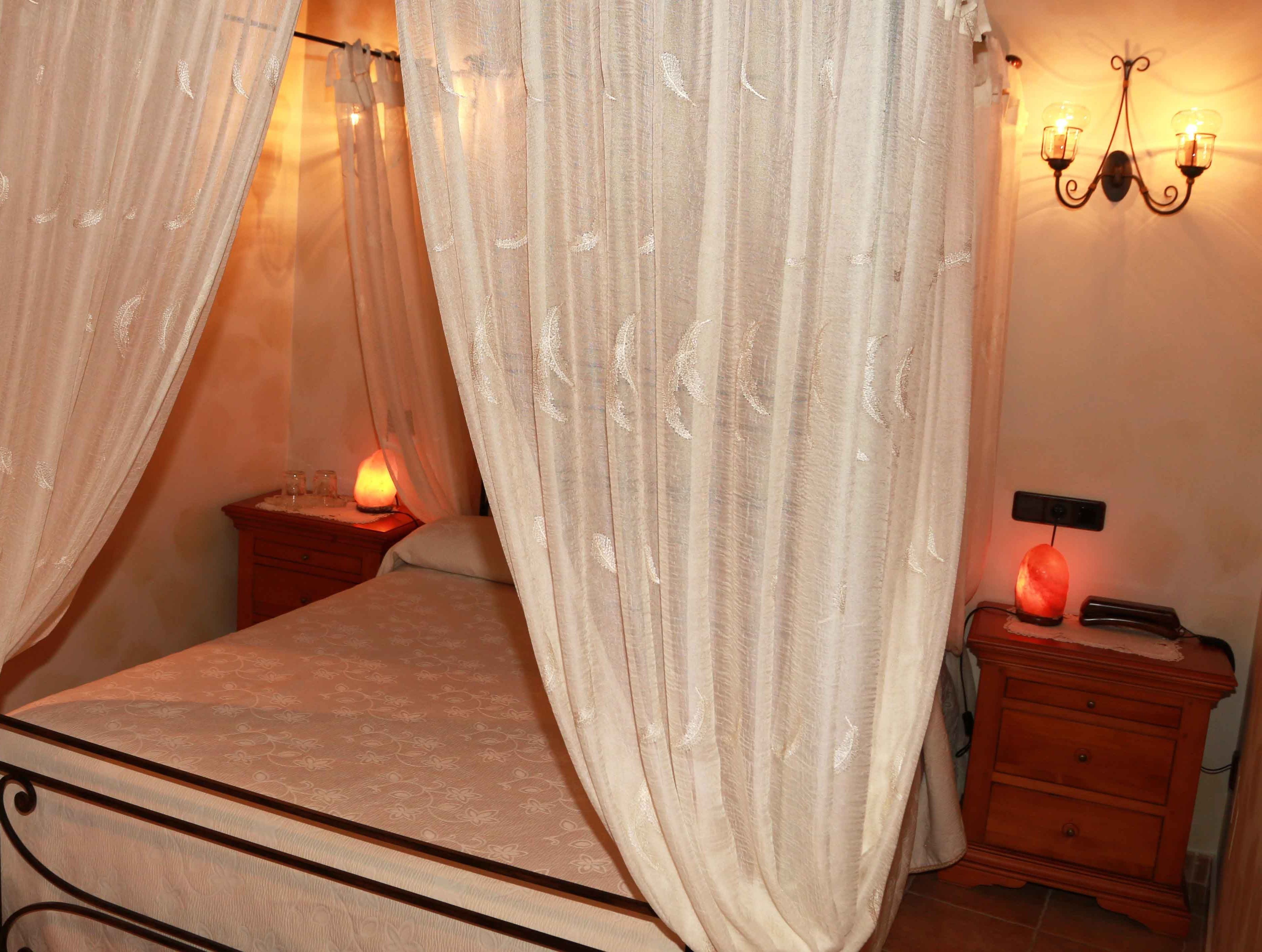 Una camera da letto con un letto, un comodino, un termosifone e una lampada a parete.