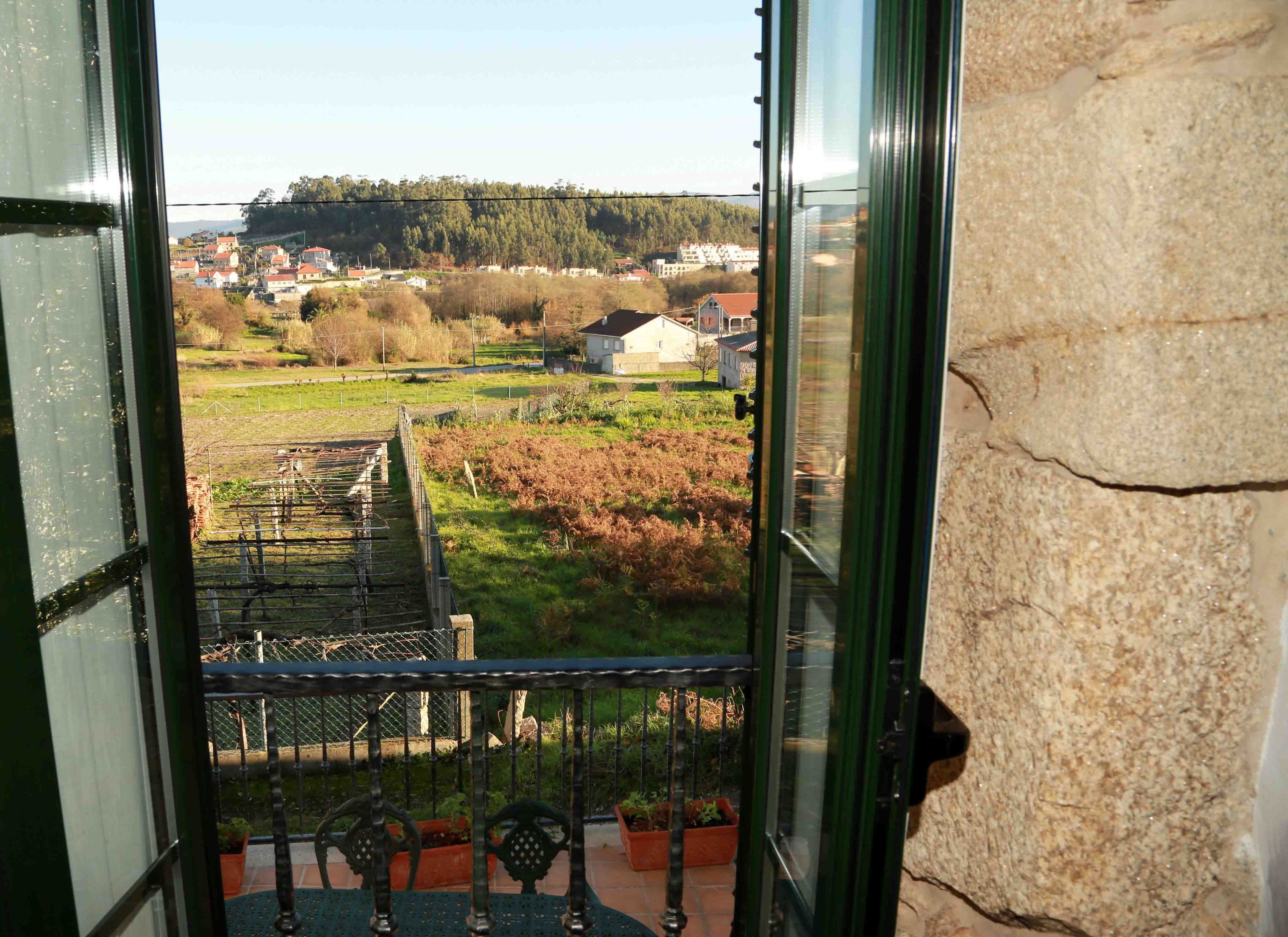 A balcony with a view of a rural landscape, including fields and houses.