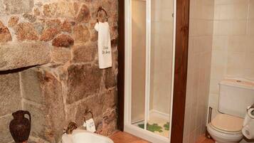 Ein Badezimmer mit Steinwand, Duschkabine, Toilette und Waschbecken.