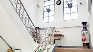 Un escalier orné de rampes en métal ouvragé, une horloge et un vase décoratif.