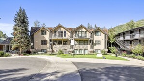 A multi-story hotel with a stone facade, balconies, and a landscaped driveway. - Ute Condominiums - Central & Cozy (Aspen)