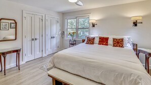 A bedroom with a large bed, a bench, a desk, and a window with a view of trees. - Ute Condominiums - Central & Cozy (Aspen)