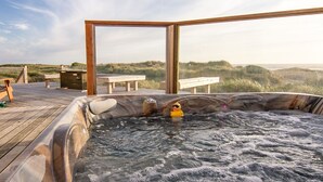 A hot tub with a wooden deck, a duck, and a bench in a natural setting. - Oceanfront on Sandy Beach! Hot Tub! Dog Friendly! Direct Beach Access! Game Room! (Waldport)