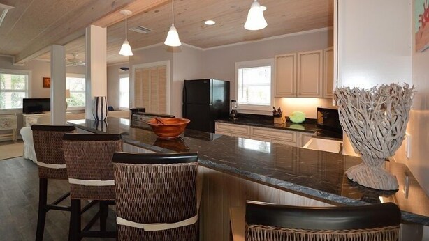 Una cocina moderna con una isla grande, taburetes de bar, iluminación colgante y una pieza decorativa original.