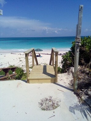 A wooden staircase leading to a beach with clear turquoise water.
