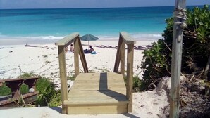Una escalera de madera que lleva a una playa con agua turquesa cristalina.