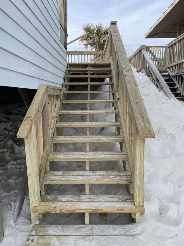 Una escalera de madera que conduce a un edificio de fachada blanca.
