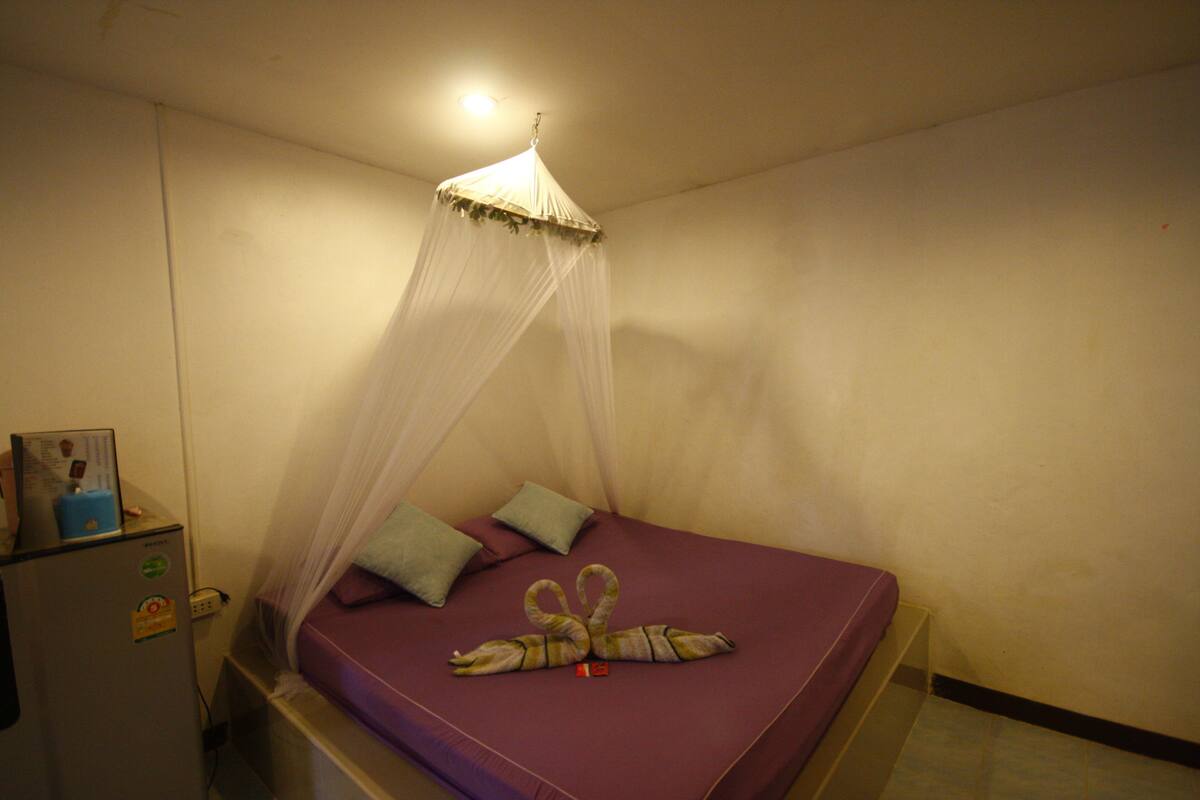 A room with a bed, a bedside table, and a ceiling fan.