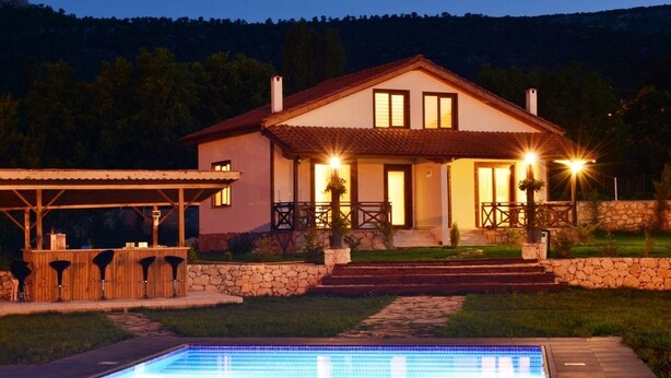 Ein zweistöckiges Haus mit Schwimmbad, Steintreppe und Außenbeleuchtung.