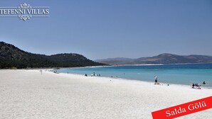 Ein Strand mit klarem türkisblauem Wasser und weißem Sand, beschriftet mit 'Salda Gölü' und 'TEFENNI VILLAS'.