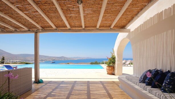 A covered outdoor area with a pool, seating, and a view of the sea. - Spacious Luxury Villa Delion-stunning sunset&bay view, infinity pool, by beaches (PAROS)