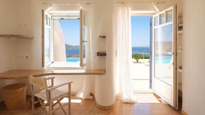 A room with a wooden desk, a chair, and a view of the sea through open doors. - Spacious Luxury Villa Delion-stunning sunset&bay view, infinity pool, by beaches (PAROS)