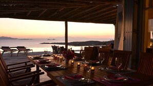 A dining table set for two with a view of the sea at sunset. - Spacious Luxury Villa Delion-stunning sunset&bay view, infinity pool, by beaches (PAROS)