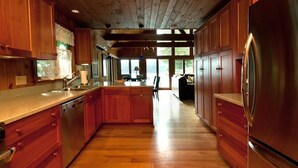 A spacious kitchen with wooden cabinets, a stainless steel refrigerator, and a large island. - Private Lakeside near Burlington, Oversized Dock Skiing, Shopping, Fine Dining (Colchester)