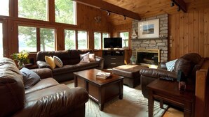 A cozy living room with a stone fireplace, leather sofas, and a television. - Private Lakeside near Burlington, Oversized Dock Skiing, Shopping, Fine Dining (Colchester)