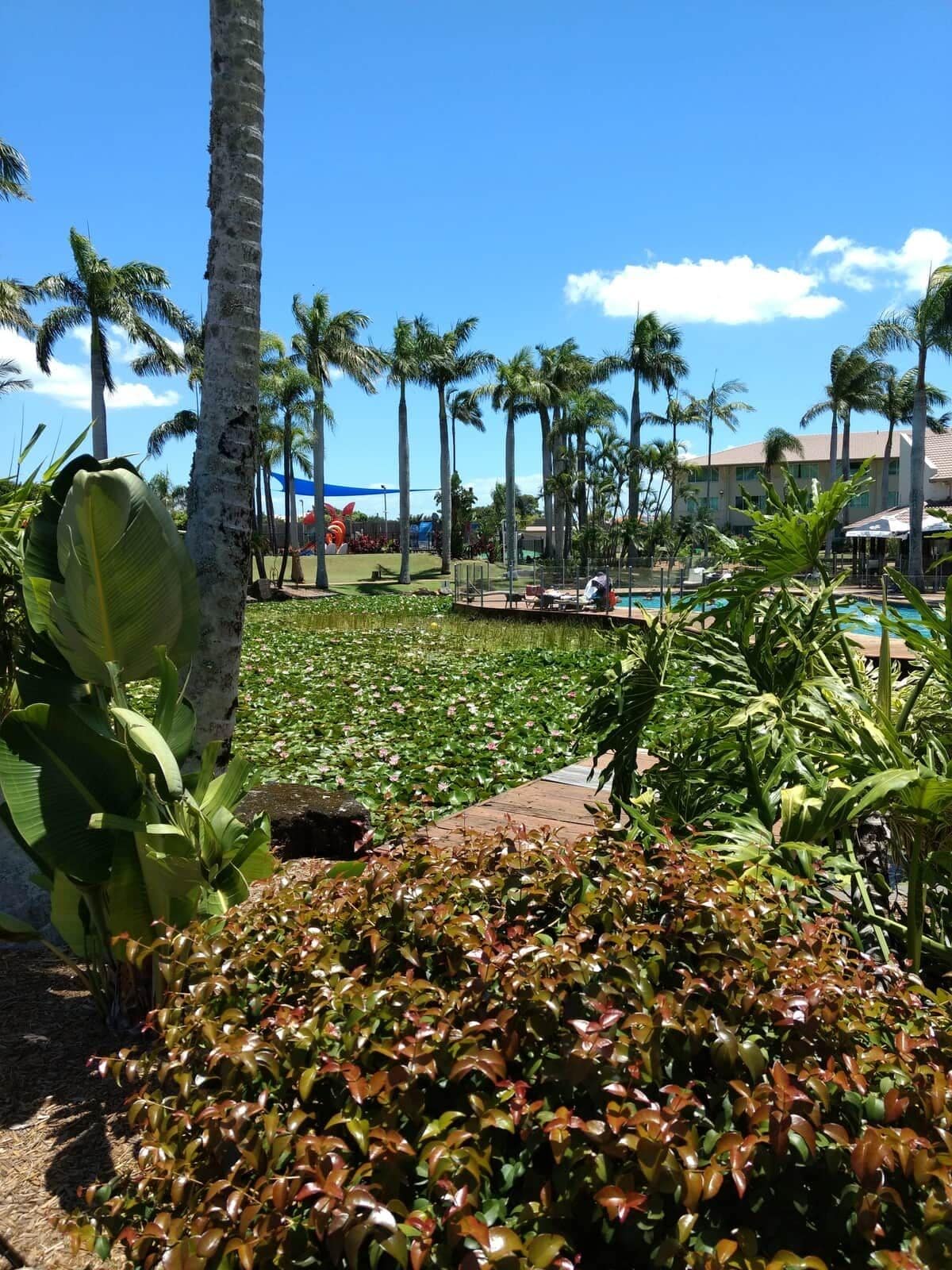 Ein Resort mit Pool, Palmen und einem Gebäude im Hintergrund.