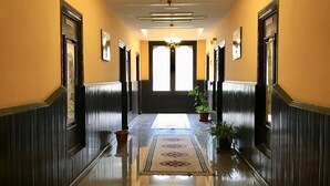 A hallway with a chandelier, a large window, and a potted plant. - Hotel Migmar (Thimphu)