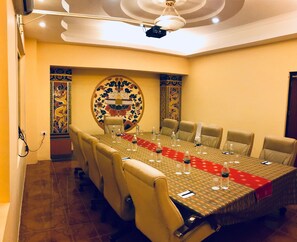 Una sala de conferencias con una larga mesa, sillas y un adorno en la pared.