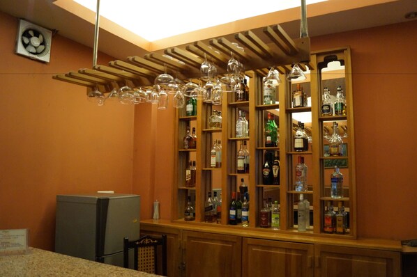 Una zona de bar con estantes llenos de botellas de licores y copas de vino.