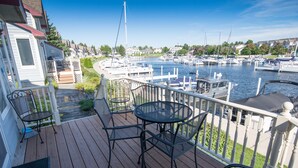 Una terraza de madera con muebles de exterior con vistas a un puerto deportivo con barcos.