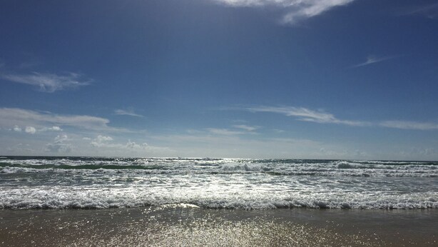 Una playa con olas y cielo despejado.